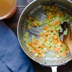 a pot filled with chopped vegetables next to a wooden spoon