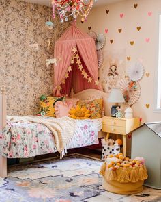 a child's bedroom decorated in pink and gold with a canopy bed, dressers, toys and other accessories