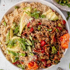 a white bowl filled with rice and veggies on top of a table next to silverware