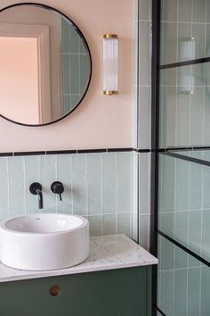 a white sink sitting under a round mirror in a bathroom