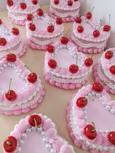 many pink cakes with cherries on them