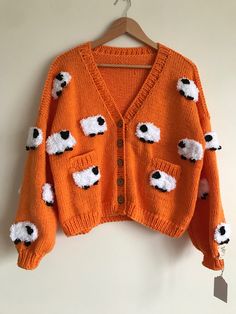 an orange sweater with black and white sheep on it