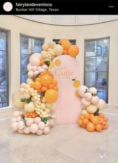 an orange and white balloon arch in the middle of a room