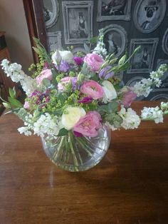 a vase filled with lots of flowers on top of a wooden table next to a mirror