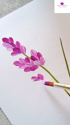 purple flowers are being painted on white paper