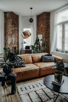 a living room filled with lots of furniture next to large windows and potted plants