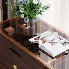 a vase with flowers and an open book on a table