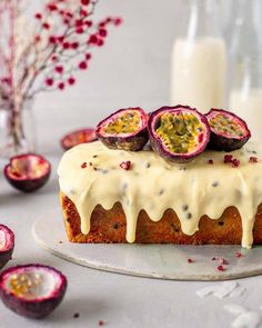 a cake with white frosting and fruit on top sitting on a plate next to some candles