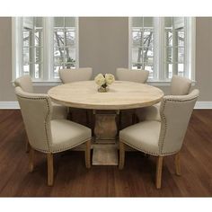 a round table with four chairs around it in front of two windows and hardwood floors