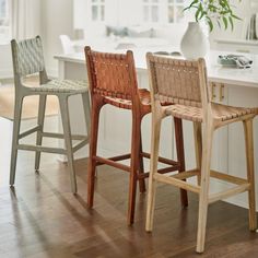 three wooden stools sitting in front of a white counter top next to a window