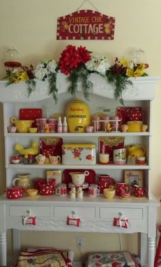 a white shelf filled with lots of food and flowers on it's top, next to a wall sign that says cottage cottage