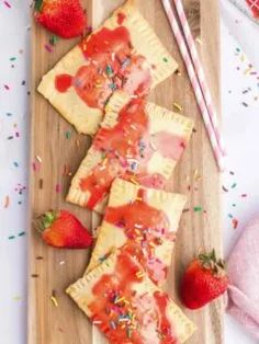 strawberry shortcakes with icing and sprinkles on a cutting board