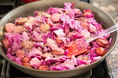 a pan filled with red cabbage and meat on top of a stove burner next to an oven