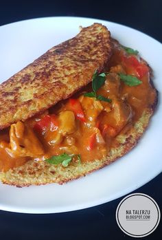 a white plate topped with two pieces of bread covered in sauce and veggies