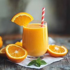 an orange smoothie in a glass with a straw and two slices of orange next to it