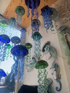 several glass jellyfish hanging from the ceiling in a room with a mirror and window