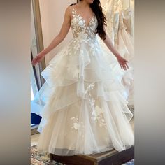 a woman standing in front of a mirror wearing a white dress with flowers on it