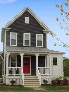 a black and white two story house with red door on the front porch is shown