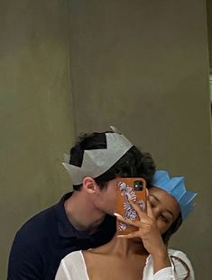 a man and woman taking a selfie in front of a mirror with paper crowns on their heads