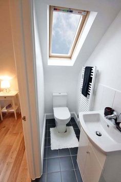 a small bathroom with a toilet, sink and radiator next to a window