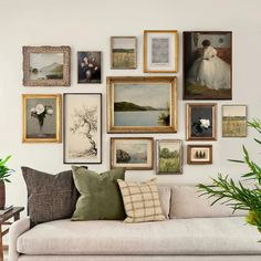 a living room filled with lots of framed pictures on the wall next to a couch