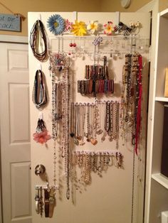 a wall mounted jewelry rack filled with lots of necklaces and bracelets on it