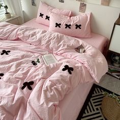 a bed with pink sheets and black bows on it