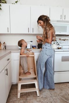 a woman standing next to a baby in a high chair