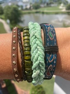 three different bracelets on someone's arm with water in the background