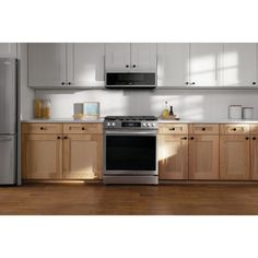 an empty kitchen with stainless steel appliances and wood cabinets is pictured in this image from the front view