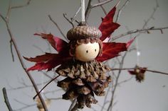 an ornament hanging from a tree with red leaves and a doll on it