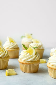 several cupcakes with white frosting and lemon wedges on the top one