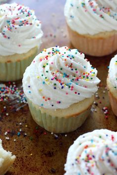 several cupcakes with white frosting and sprinkles