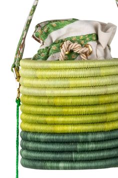 a green and yellow coiled basket with a white bag in it's back pocket