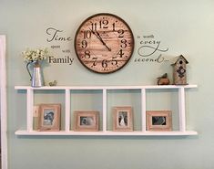 a clock mounted to the side of a wall next to pictures and frames on a shelf