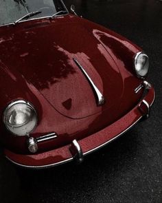 an old red sports car parked on the street