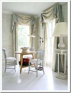 a living room filled with furniture and a lamp on top of a wooden table next to a window