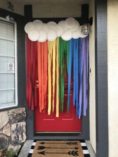 the front door is decorated with rainbow streamers and white balloons hanging from the ceiling