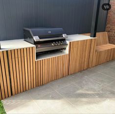 an outdoor grill built into the side of a building with wood slats on it