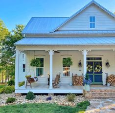 a white house with a porch and front door covered in wreaths on the porch