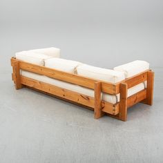 a couch made out of wood with white cushions