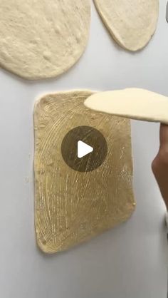 a person is making pizza dough on a white surface with a spatula in front of them