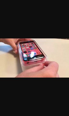 a person holding an iphone in their hand on top of a white table with other items