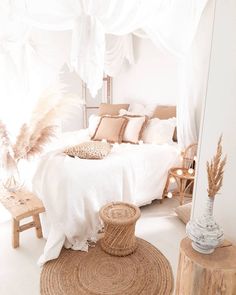 a white bedroom with lots of pillows and blankets