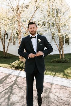 a man in a tuxedo is standing outside