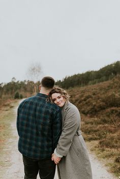 a man and woman standing next to each other on a dirt road