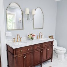 a bathroom with two sinks and mirrors on the wall next to a toilet in it