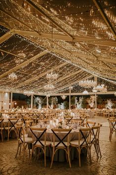 the inside of a tent with tables and chairs set up for a wedding reception at night