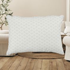 a white pillow sitting on top of a wooden floor next to a chair and potted plant