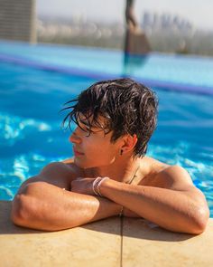 a young man sitting in the middle of a swimming pool